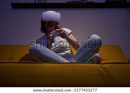Woman with virtual reality headset and joystic is playing game.