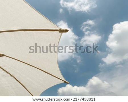 A white umbrella for sun protection during the day with a beautiful sky and clouds background.