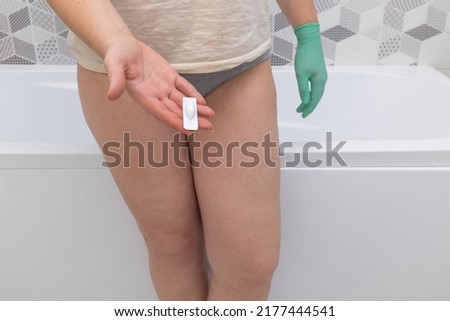 Concept of Gynecology, woman health. Woman in panties holds a Vaginal or rectal suppository against the backdrop of a bathroom. Concept of Gynecology, woman health.
