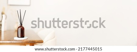 Aroma reed diffuser home fragrance with rattan sticks on a light background on wooden table in living room, banner. Royalty-Free Stock Photo #2177445015