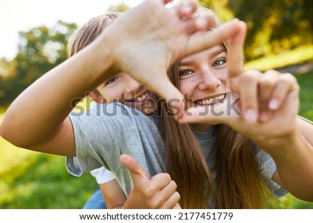 Brother and sister form a square with their hands while playing in nature