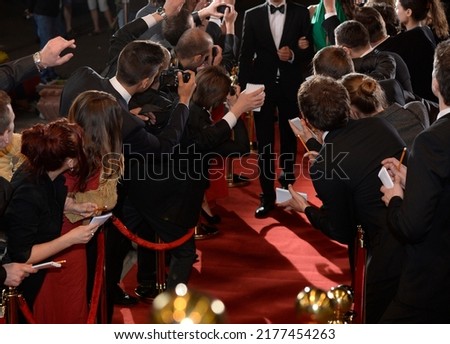 celebrity on the red carpet. man and woman in evening dresses among photographers and fans on the red carpet Royalty-Free Stock Photo #2177454263