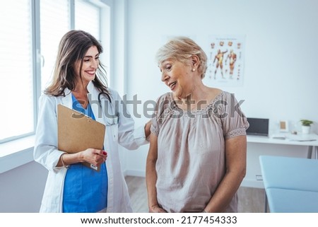 Happy senior woman visiting doctor and listening to her advice during appointment. Nurse Showing Patient Test Results On Clipboard. Doctor and patient standing in doctor's office