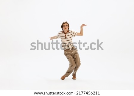 Portrait of expressive young man in vintage outfit dancing, posing isolated over white studio background. Feeling good. Concept of retro fashion, style, youth culture, emotions, beauty, ad Royalty-Free Stock Photo #2177456211