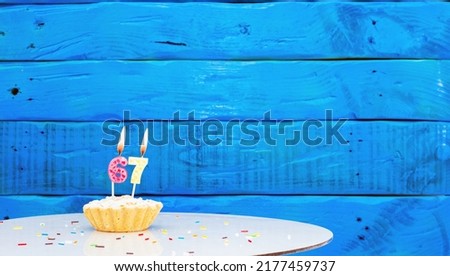 Festive background with a cake on the background of blue boards, copy space, a beautiful background for a birthday with a number a candle with a figure 67
