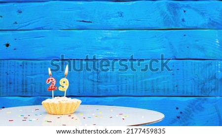 Festive background with a cake on the background of blue boards, copy space, a beautiful background for a birthday with a number a candle with a figure 29