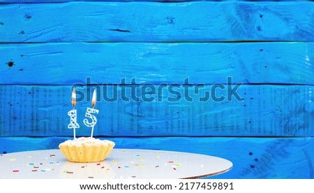 Festive background with a cake on the background of blue boards, copy space, a beautiful background for a birthday with a number a candle with a figure 15
