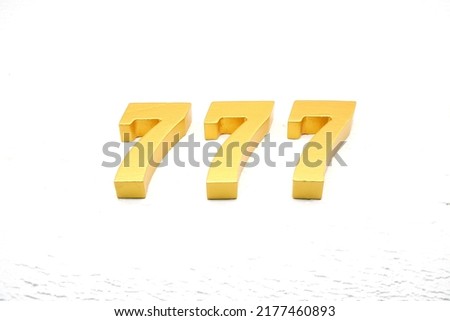    Number 777 is made of gold painted teak, 1 cm thick, laid on a white painted aerated brick floor, visualized in 3D.                                      Royalty-Free Stock Photo #2177460893