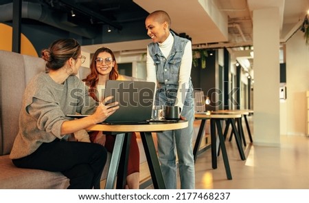 Group of young businesswomen working together in an office lobby. Three happy businesswomen having a discussion in a modern co-working space. Young female entrepreneurs collaborating on a new project. Royalty-Free Stock Photo #2177468237