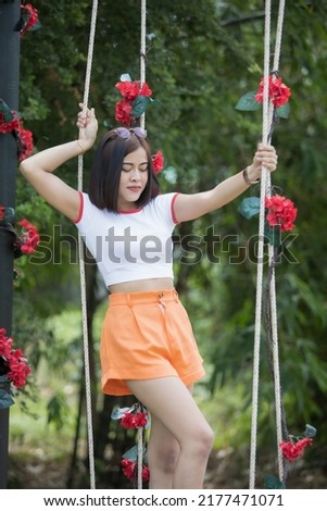 A smart woman model short hair in white shirt and orange shorts, she acting for take a picture on swing is happy, take a photo on cafe and indoor ,outdoor studio