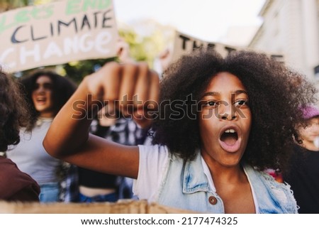 Multiethnic teenagers taking action against climate change. Group of climate activists shouting slogans while marching in the streets. Diverse young people joining the global climate strike.