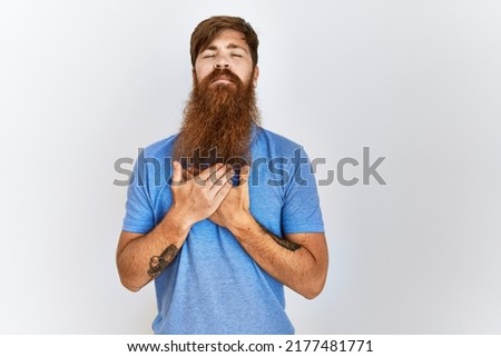 Caucasian man with long bear standing over isolated background smiling with hands on chest with closed eyes and grateful gesture on face. health concept. 