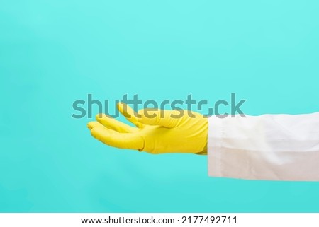 A doctor in a medical gown and protective gloves holds out an empty hand. The face is not visible. Template for adding an item to the hand.