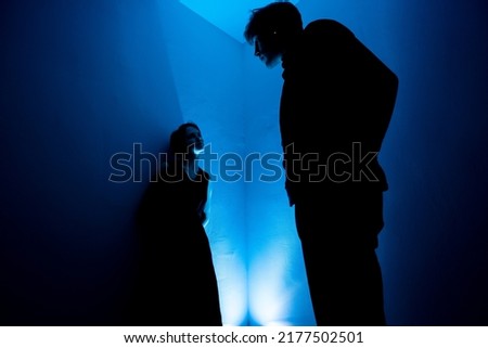 Giant man looking down at a woman. Conversation between a man and a woman in a dark room Royalty-Free Stock Photo #2177502501