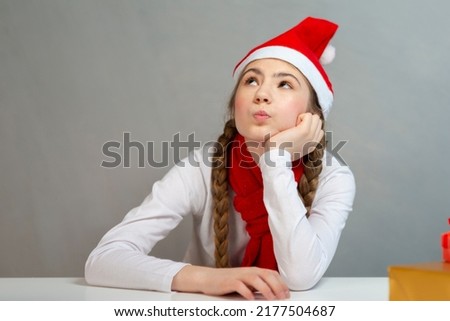 Holidays Seasonal Ideas. One Winsome Dreaming Caucasian Female Girl in Santa Hat and White Shirt With Wrapped Giftboxes Relaxing and Thinking. Horizontal image