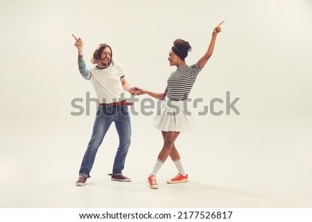 Hippie. Stylish man and woman in vintage retro style outfits dancing isolated on white background. Timeless traditions, 1960s american fashion style and art. Dancers look happy, delighted Royalty-Free Stock Photo #2177526817