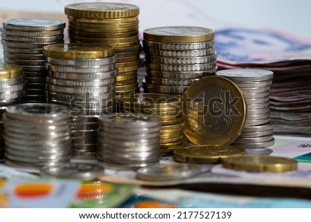 Stack of credit cards with Ukrainian hryvnia cash and euro coins, close-up view.