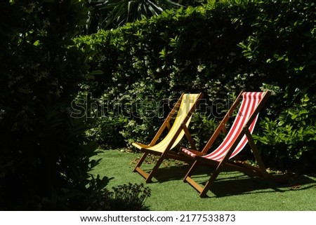 A photo of two colorful deck chairs sitting in a sunny garden. 