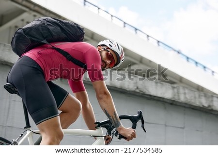 cyclist with a backpack while riding in the city on an exorbitant bike. Man in sportswear and a helmet rides the city square on a bike. Traveling around the city on a bicycle. Royalty-Free Stock Photo #2177534585