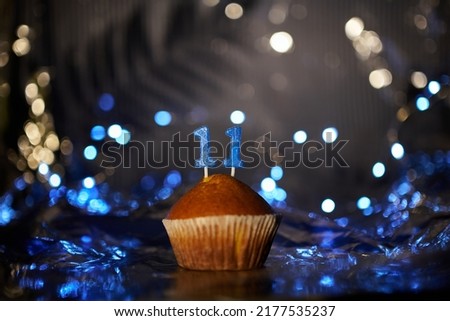Digital gift card birthday concept. Tasty fresh homemade vanilla cupcake with number 11 eleven on aluminium foil and blurred bright background in minimalistic style. High quality image