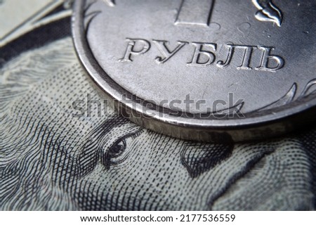 a coin with a face value of 1 ruble lies on a banknote of the American dollar. close-up. Translation of the inscription on the coin "1 ruble"