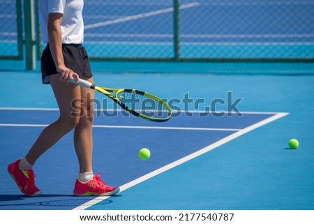 A girl plays tennis on a court with a hard blue surface on a summer sunny day Royalty-Free Stock Photo #2177540787