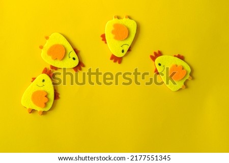 Four yellow felt decorative chickens arranged in a semicircle on a yellow background. Minimal concept, cute Easter card with a copy of the place for the text.