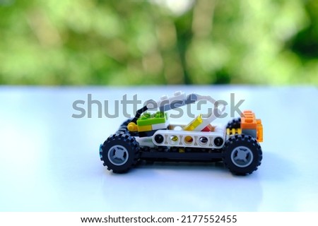 transformer car with manipulator, assembled from designer parts, beautiful green background of trees with bokeh, concept of development of fine motor skills, creativity, children's entertainment