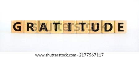 Gratitude symbol. The concept word Gratitude on wooden cubes. Beautiful white table, white background. Business and gratitude concept. Copy space.