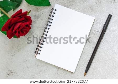 Note book with pen and roses on marble table. Directly above. Flat lay. Copy space.