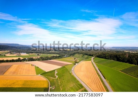 Aerial view of harvest of agricultural fields with gravel road at village of Andelfingen, Canton Zürich, on a sunny summer morning. Photo taken July 12th, 2022, Andelfingen, Switzerland.