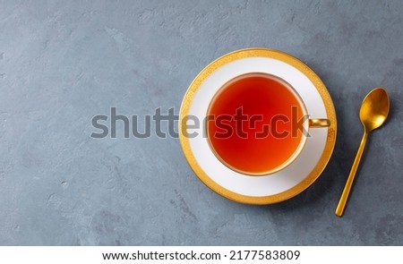 Tea in white cup with gold spoon. Grey background. Copy space. Top view. Royalty-Free Stock Photo #2177583809