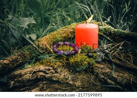 burning candle, a symbol of the moon, an amulet lying on the moss on a dark natural background. pagan wiccan, slavic traditions. Witchcraft, esoteric spiritual ritual for mabon, halloween, samhain.  Royalty-Free Stock Photo #2177599895