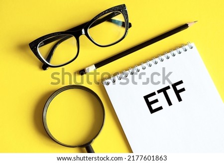 White notebook with inscription Exchange Traded Funds written in black pencil on a bright yellow background.