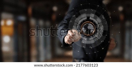 Businessman shows through a magnifying glass a globe on a virtual computer screen.
