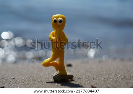 A toy zombie in a yoga pose meditates on the seashore.