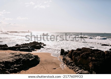 Photo of ocean waves with stone beach in sunlight. Exotic landscape with blue sky and spring ocean 