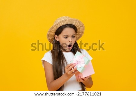 shocked teen kid hold gift box on yellow background
