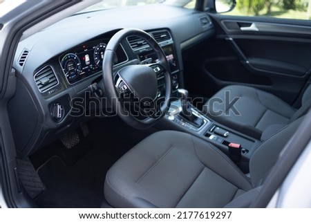 Car dashboard with a digital touchscreen. Steering wheel of a electric vehicle, interior cockpit, electric buttons, digital speedometer, front seats, textile, windows, console, gear shift. Royalty-Free Stock Photo #2177619297