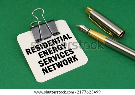 Business and industry concept. On a green surface, a pen and a sheet of paper with the inscription - Residential Energy Services Network