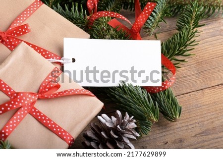 Christmas rectangle gift tag mockup with present box, product label mockup, with natural fir tree branch, cones and Christmas decoration, Christmas sale concept. Blank paper rectangular name tag
