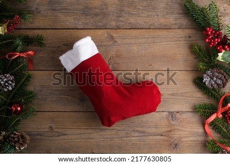 Red Christmas stockings on a rustic wooden wall background with Christmas decoration, fir tree and cone, red ribbon. Epiphany Befana's stockings or Santa Claus stocking for sweet