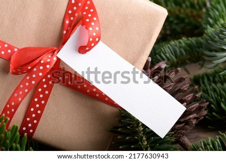 Christmas rectangle strip gift tag mockup with present box, product label mockup, with natural fir tree branch, cones and Christmas decoration, Christmas sale concept. Blank paper rectangular name tag