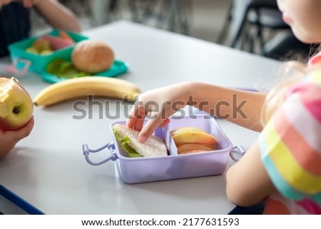 School children eating healthy food from packed lunch boxes. Kids at table in cafeteria. Pupils have vegetarian breakfast in canteen. Back to school concept. Lifestyle moment in elementary college Royalty-Free Stock Photo #2177631593