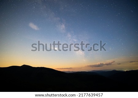 Beautiful panorama of bright blue sky with shining stars and milkyway over dark mountains landscape at night