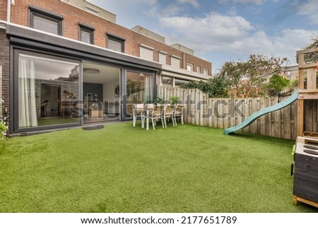 Neat paved patio with sitting area and small garden near wooden fence Royalty-Free Stock Photo #2177651789