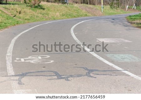 White bicycle sign on an asphalt bike lane in a city park. Track. Asphalt. Cyclist. Lane. Healthy. Line. Symbol. Outdoor. Travel. Ride. Safety. Way. Health. Biking. Urban Royalty-Free Stock Photo #2177656459