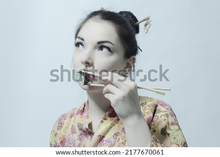 Young beautiful asian woman eating sushi over white background