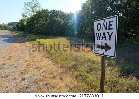 One Way road sign, on a gravel road in a rural area. 