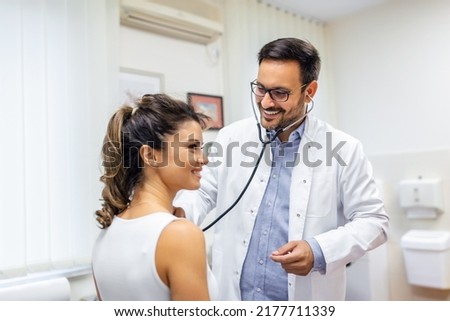 Young doctor listen to female patient heart chest with stethoscope at clinic meeting. Man GP checkup examine woman client with phonendoscope. healthcare concept. Royalty-Free Stock Photo #2177711339